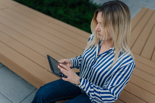 Woman using a tablet outdoors in city park
