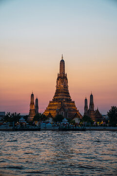 Wat arun temple illuminated at sunset by chao phraya river
