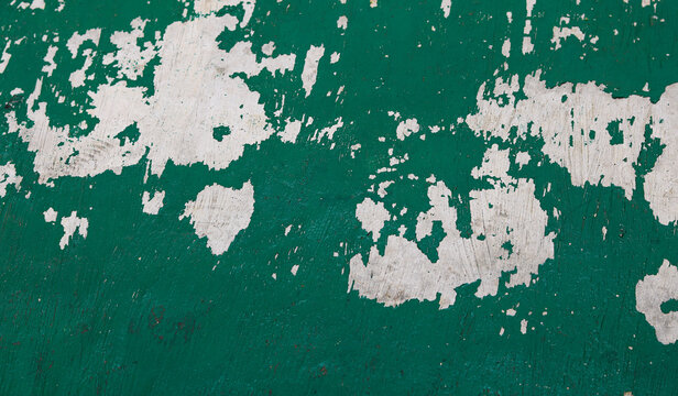Chipped green paint and cracked white concrete texture.