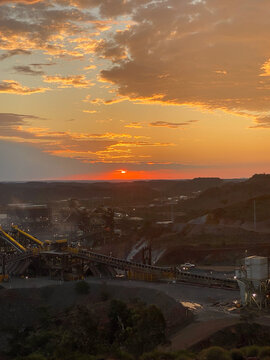 Industrial mining operation at sunset with conveyors transporting ore