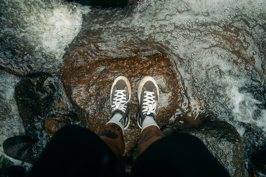 Point of View of Feet Standing on River Rock Over Flowing Water