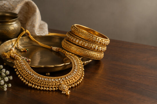 South Asian gold necklace and bangles on brass tray, jewelry arrangement