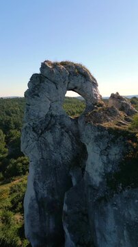 Aerial view of natural rock arch at Maczuga Herkulesa in southern Poland. Unique limestone formation surrounded by forest in the Jura region.