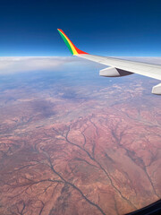 Fototapeta premium Airplane wing flying over arid desert landscape