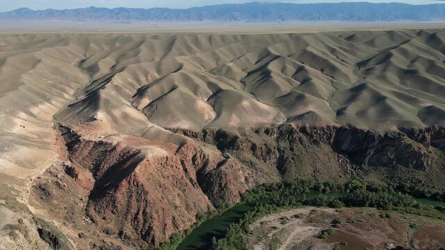 The drone flies over the Black Canyon and the Charyn River, revealing views of the arid, hilly terrain and mountains stretching to the horizon