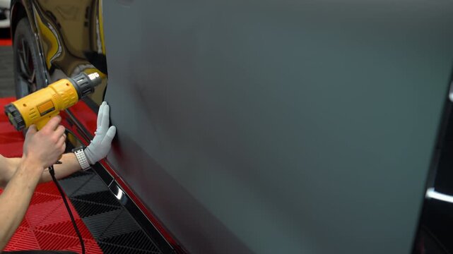 Close up footage of process installed vinyl film on a car in a workshop. detailing process with film installation, smooth matte finish and precision work