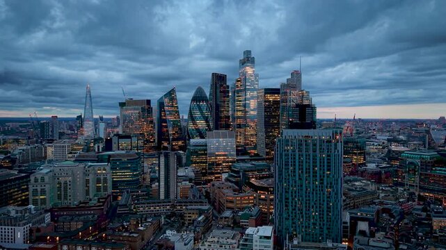 Aerial view of the illuminated office skyscrapers and the skyline at the City of London, England, during a moody evening with clouds