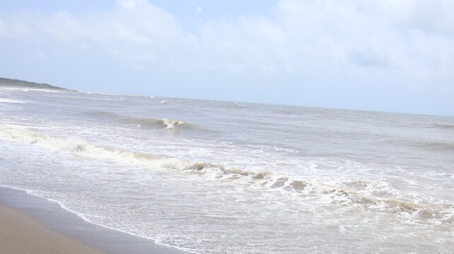 Gentle Ocean Waves Flowing Onto a Sandy Beach Under a Cloudy Sky