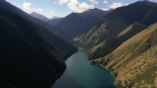 Majestic aerial footage flying over the tranquil turquoise waters of kolsay lake, nestled in a deep valley surrounded by forested mountains