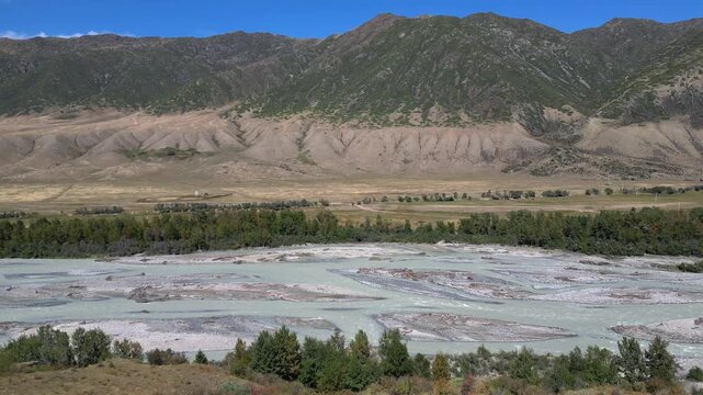 Stunning aerial view of the chilik river valley in kazakhstan. Majestic tien shan mountain range dominates the background on a sunny day