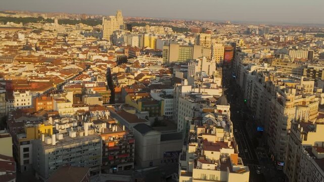 High angle aerial shot of Madrid city center buildings and Gran Via street during a warm sunset. Ideal for travel documentaries, urban planning, and European tourism content.