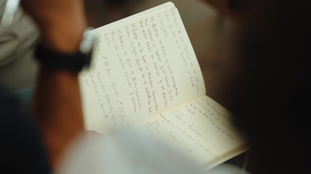 Person writing or reading handwritten text in a journal, focusing on education, planning, or personal development