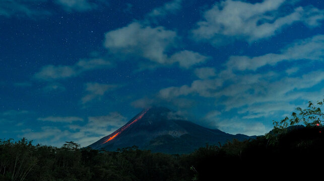 Mount merapi volcano erupting lava flow at night