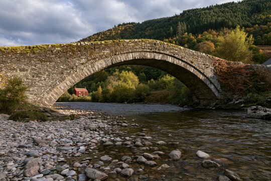 The Stone Arch Bridge Over a Quiet River in Autumn Countryside Landscape