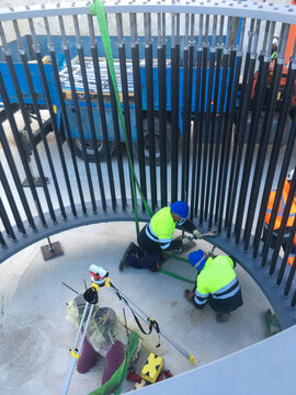 Workers constructing wind turbine foundation using anchoring bolts