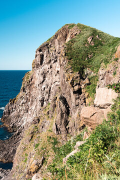 Rugged volcanic sea cliff towering over the deep blue waters of Rishiri Island, Hokkaido