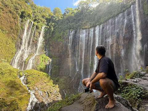 Man observing tumpak sewu waterfall in indonesia