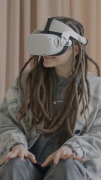 Slow motion of young woman with dreadlocks using virtual reality glasses enjoying cool gadget in luxury apartment. Augmented reality goggles and fun concept.