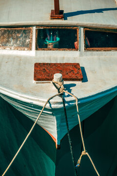 Classic wooden boat tied at a dock in Kvarner Bay, Croatia, reflecting in serene harbor waters. Concept of traditional maritime craft, nautical heritage, and coastal travel.