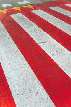Vivid red white and yellow pedestrian road markings on an urban street. Concept of traffic safety, pedestrian crossing, caution, and road infrastructure.