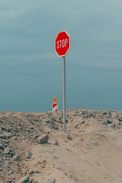 Solitary stop sign erected on a rocky dirt ridge at a road construction site. Concept of regulatory warning, traffic control, work zone hazard, and surreal isolation.