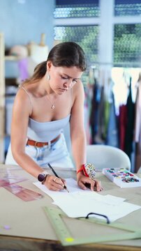 Young thoughtful dressmaker draws a sketch on paper. Fashion designer prepares a drawing according to which he will sew clothes . High quality 4k footage