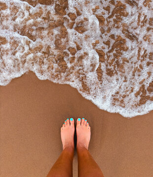 Top down view of a woman's feet on a red andy beach