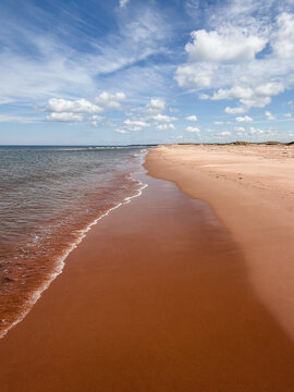 Gentle waves lap on a famous red sand beach in PEI, Canada