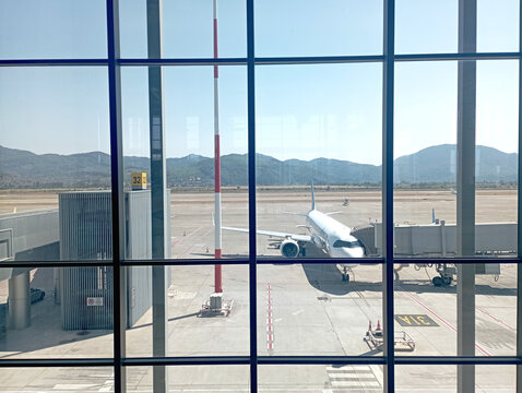 An airplane docked at the jet bridge at Dalaman Airport on 7 September 2026. View of the runway from the airport window. Vacation, travel, or overseas theme.