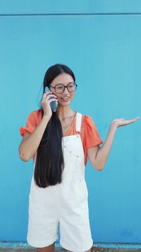 Young asian woman happily talking on her smartphone