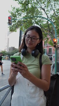 Young asian woman using a smartphone while waiting in the city, back to university.