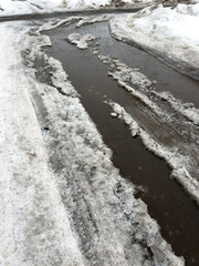 Obraz premium Snowy roadside with melting water flowing through icy channels
