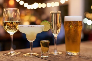 Naklejka premium The Assorted Bar Drinks on Wooden Table Under Warm Bokeh Lights