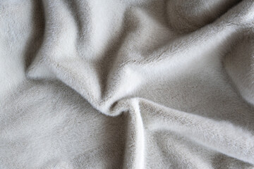 Soft gray wool blanket close-up texture with cozy fur pile for interior. Gentle folds for home. © Iryna