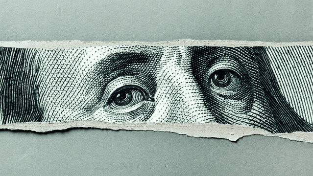 Close-up of eyes from a torn piece of a dollar bill showing currency detail