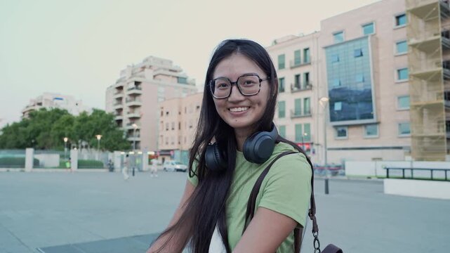 Happy asian woman with glasses smiling at camera outdoors