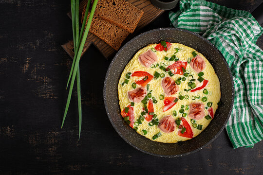 Homemade Omelet with Sausage, Tomatoes and Green Onion in Frying Pan. Top view