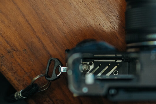 close-up view showing the open battery compartment and internal contact pins of a camera resting on a wooden surface.