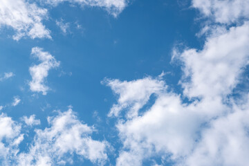 Fototapeta premium Blue sky with fluffy white cumulus clouds scattered across the horizon, providing natural copy space for design, wallpaper, or serene background use. 