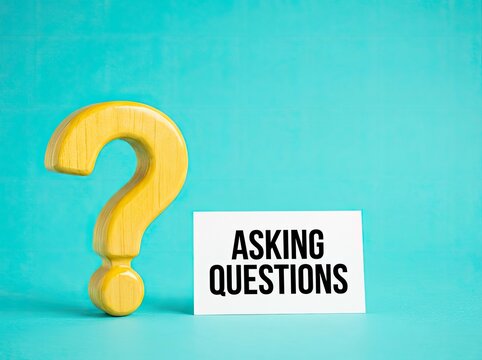 Wooden question mark next to asking questions card on blue background ideal for FAQ and business content representing inquiry and seeking solutions