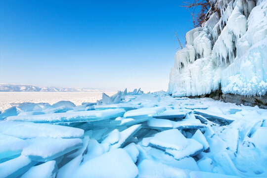 Ice floes with snow on Baikal lake in winter. Icicles on the rocks of Olkhon isalnd. Baikal, Siberia, Russia.