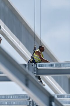 Precast wall panel being lowered by a focused rigger in a hi-vis vest, showing gritty textures for construction and engineering coverage