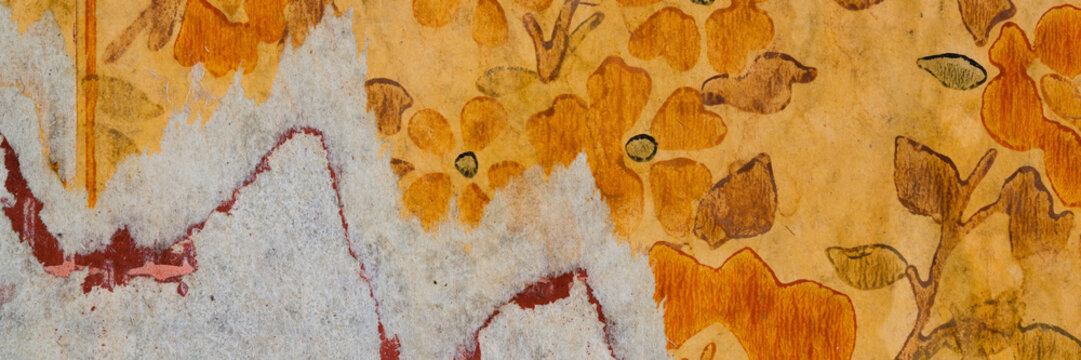 Torn old faded paper wallpaper with a retro pattern. Tattered scraps of paper on the wall. Wide panoramic texture for background and design.