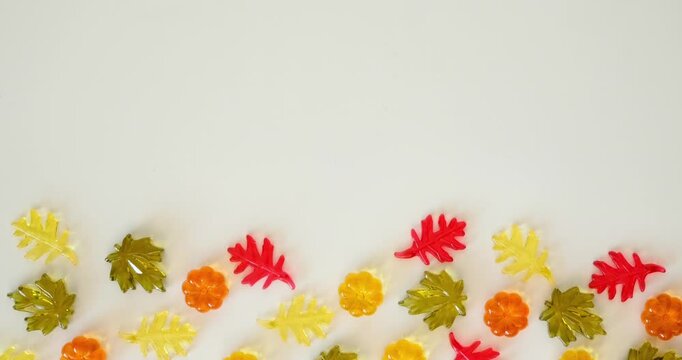 Border made of multicolored glass autumn leaves and pumpkins, with space for text at the top; white background. Looped 4K stop motion animation