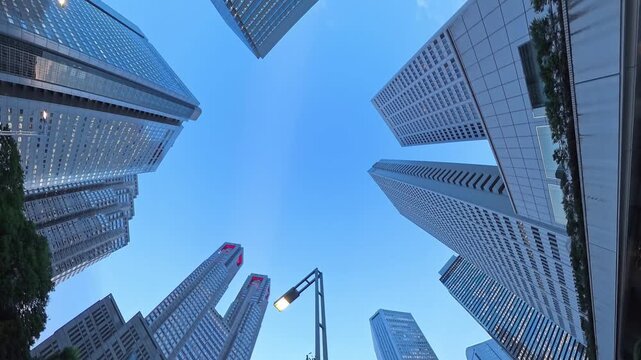 TOKYO, JAPAN - JUL 2026 : Skyscrapers and office buildings in Nishi-Shinjuku business district. Looking up from below at sunset. Japanese corporate business, financial hub and urban technology concept