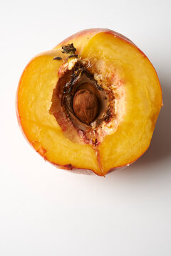 Halved peach with visible pit, close-up top view showing juicy yellow flesh on a light background