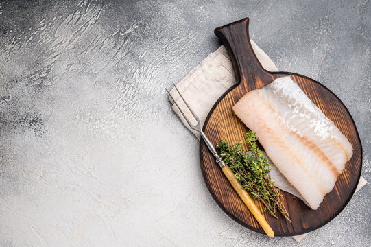 Tender Pacific cod loin, raw fish fillet featuring a light hue and flaky texture, perfect for pan-searing or steaming. grey background. top view
