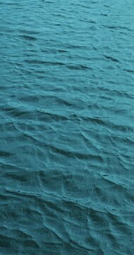 Blue lake water ripples in calm motion, showing textured surface waves and gentle movement across open sea. Lake water stays abstract and natural in tranquil marine pattern.
