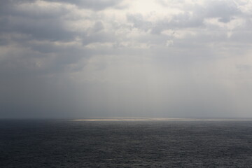 Fototapeta premium Sunlight breaks through dark clouds over the sea.