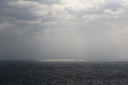 Sunlight breaks through dark clouds over the sea.